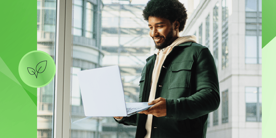 Homem sorridente usando um laptop em um ambiente moderno e iluminado, transmitindo uma sensação de produtividade e inovação. Ideal para temas de tecnologia e meio ambiente.